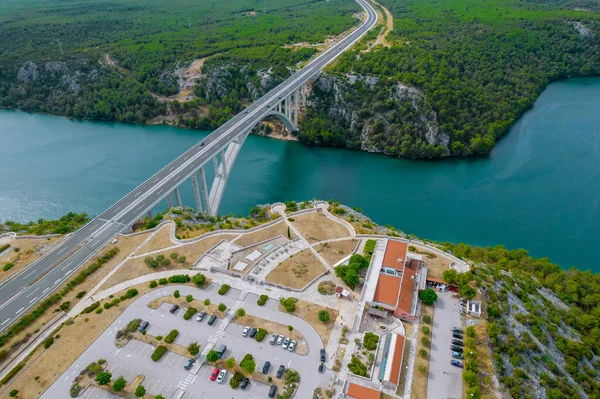 Bridge over the sea in Croatia, parking by the highway. Top view of the nature of rocky green pine forests.