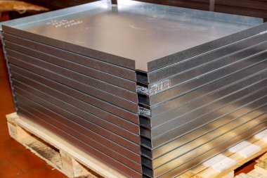 Sheet metal bending on a hydraulic machine at the factory. A stack of bent thin sheet metal products on a pallet. Bending sheet metal with a hydraulic machine at the factory