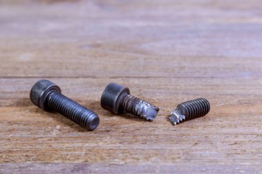 Ahşap arka planda kırılmış siyah cıvata. Sert cıvata.