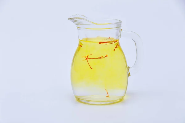 Saffron tea from red stamens in a transparent jug on a white background. Saffron drink.