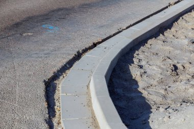 The curb is laid out next to the road. Repair works on the asphalted road.