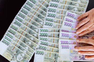 Çek tacını elinde tutan bir iş kadını. Paranın farklı mezhepleri. Siyah arka planda bir sürü Çek tacı var. Üst görünüm.