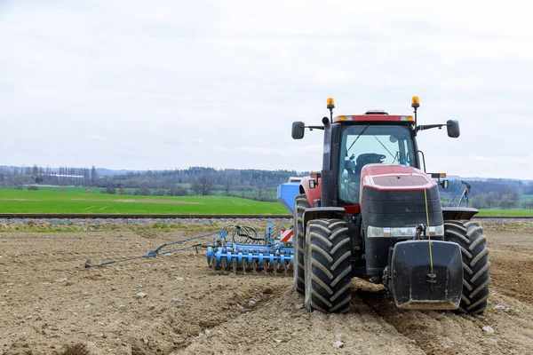 Een Grote Rode Trekker Met Zaaimachines Staat Een Veld Bij — Stockfoto