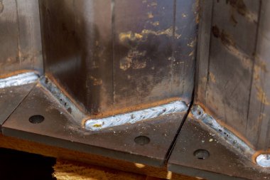 Bir kaynak, kare bir boruyu kalın bir plakaya bağlar. İnşaatta kullanılacak metal yapıların hazırlanması.