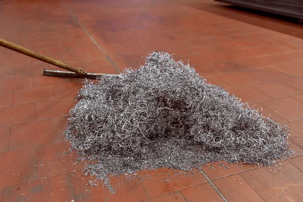 A pile of metal shavings lies on the floor in a production shop.
