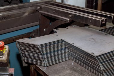 Bükme makinesinde işlem yaptıktan sonra bir yığın metal ürün..