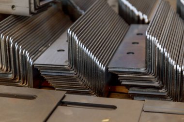Bükme makinesinde işlem yaptıktan sonra bir yığın metal ürün..
