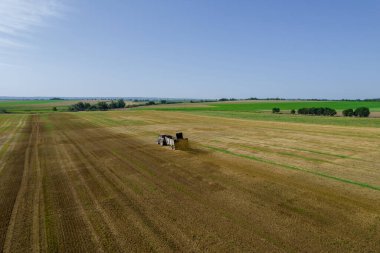 Bir traktör yakınlardaki bir karavandan büyük bir tarlaya gübre saçıyor. Toprak gübreleme. Doğal gübre. Tarım. Yukarıdan görüntüle.