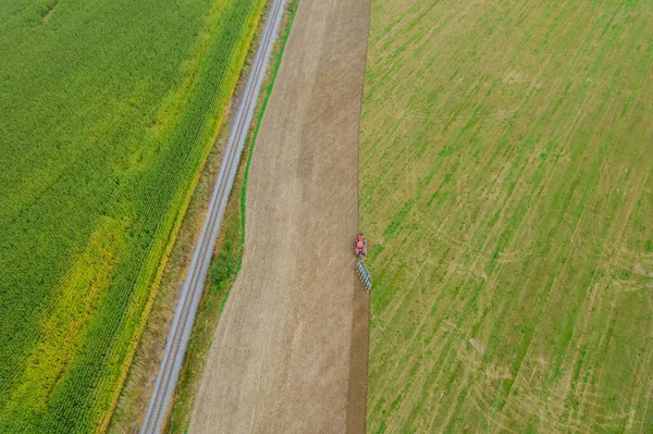俯瞰拖拉机在铁路附近耕地和玉米地的景象 在战场上工作的季节 — 图库照片