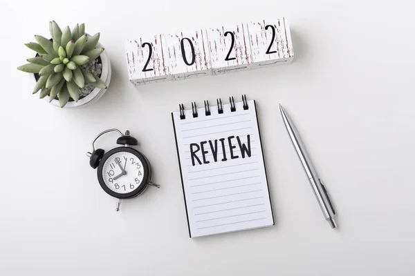2022 Not defteri ve saat ile gözden geçirme konsepti beyaz masa arkaplanı, üst görünüm