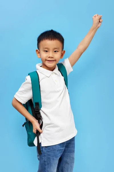 Малюк Шкільним Рюкзаком Піднімає Руку Посміхається Білій Сорочці Синьому Фоні — стокове фото