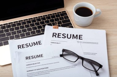 Dizüstü bilgisayarında bardak ve kahve fincanı ile tahta masada devam ediyor, incelemeye devam ediyor, iş görüşmesi yapıyor.