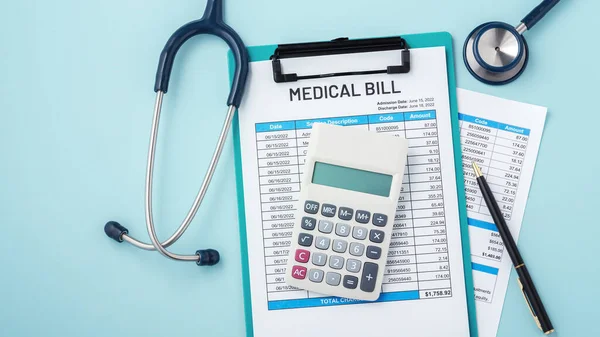 Calculator on medical bill with stethoscope and pen on blue background with copy space