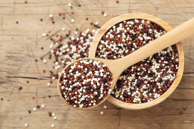 Kaşık kaşık içinde, tahta zemin üzerinde, beyaz, kırmızı ve siyah kinoa.