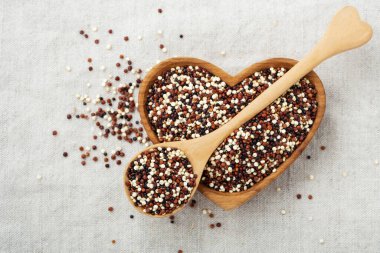 Kumaş arka planda kaşık ve ahşap bir kasede kinoa.