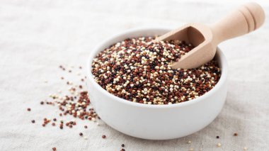 Beyaz kâse içinde, keten bezinde ahşap kepçeyle kinoa.