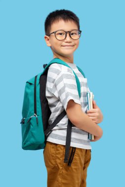Okul çantalı, gözlüklü ve mavi arka planda tişört giyen mutlu çocuk.