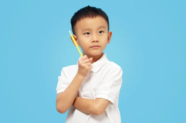 聪明的孩子交叉着胳膊 思考着 抬起头 把铅笔放在蓝色的背景上 — 图库照片