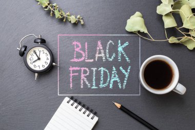 Siyah Cuma kelimesi, siyah taşa tebeşirle yazılmış kahve fincanı, kırtasiye ve yapraklar, üst manzara.