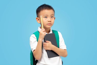 Çocuk düşünüyor, bakıyor, sıkılmış ve yorgun bir öğrenci mavi arka planda tablet tutuyor.