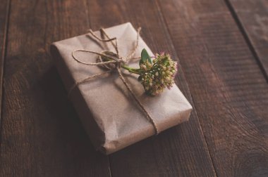 Çiçeklerle süslenmiş, ambalaj kağıdına sarılı bir hediye.