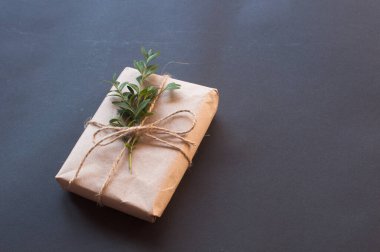 Siyah arka planda yeşil yaprakları olan doğal düğümlü bir hediye kutusu. Esmer arka planda indirim kavramı