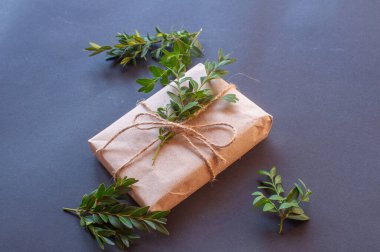 Siyah arka planda yeşil yaprakları olan doğal düğümlü bir hediye kutusu. Esmer arka planda indirim kavramı