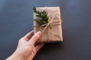 Siyah arka planda yeşil yaprakları olan doğal düğümlü bir hediye kutusu. Esmer arka planda indirim kavramı