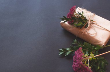 Siyah arka planda pembe küçük çiçekler olan doğal düğümlü bir hediye kutusu. Esmer arka planda indirim kavramı