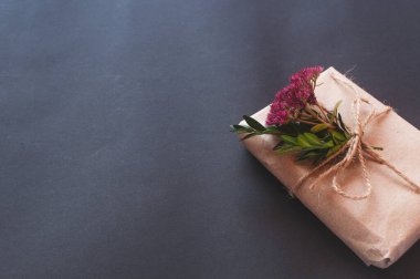 Siyah arka planda pembe küçük çiçekler olan doğal düğümlü bir hediye kutusu. Esmer arka planda indirim kavramı