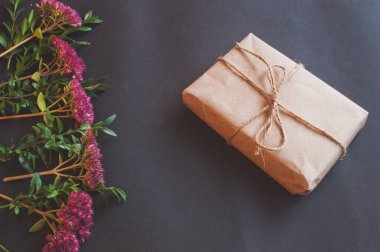 Siyah arka planda pembe küçük çiçekler olan doğal düğümlü bir hediye kutusu. Esmer arka planda indirim kavramı