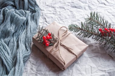 Antika masa örtüsü grisinin yanında hediye kutusu ve beyaz arka planda kırmızı böğürtlenli ladin yaprakları, açık arkaplanda şenlikli kompozisyon