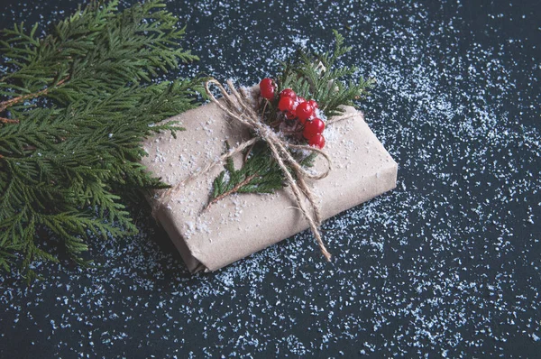Vánoční Dárková Krabice Papíru Kraft Sněhem Černém Stole Jedlovými Větvemi — Stock fotografie