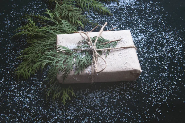 一件礼物是用黑色的纸包裹着一丛丛冷杉 在黑暗的背景上放着雪的礼盒 — 图库照片