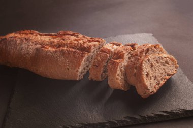 Siyah taştan bir arka planda taze çıtır Fransız ekmeği. Kıtır kıtır Fransız ekmeği paketleme. Yemek fotoğrafçılığı..