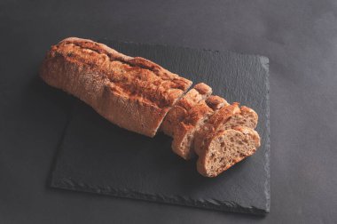 Siyah taştan bir arka planda taze çıtır Fransız ekmeği. Kıtır kıtır Fransız ekmeği paketleme. Yemek fotoğrafçılığı..