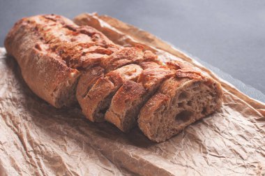 tahıl ekmeği siyah arkaplanda parşömen kağıdında parçalara ayrılmış.