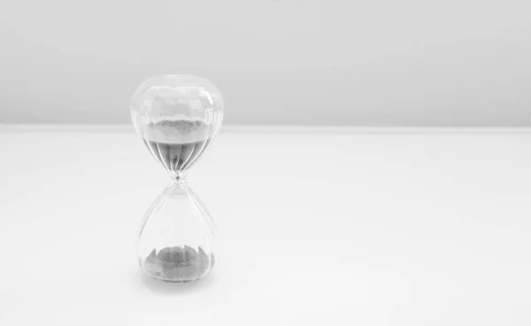 Hourglass, sandglass with sand on a white background with a streak of white light and a shadow