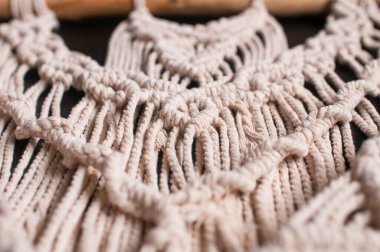 Dekorun bej rengi doğal ipliklerden örülmüş siyah arkaplanda el yapımı makrome tarzının bir parçası.