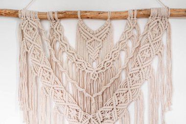 Beyaz arkaplanda örülmüş makrome biçiminde duvar dekoru