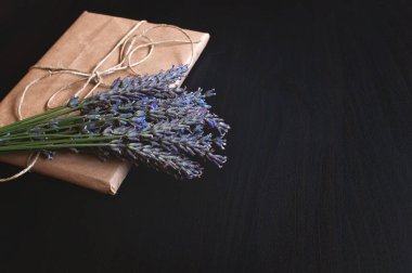 Siyah arka planda taze lavanta çiçekleri olan Kraft kağıt hediye kutusu..