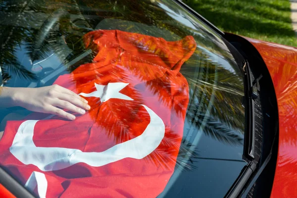 hand holding turkish flag inside car