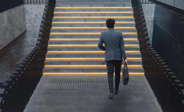 İş adamı merdivenlerden arkaya bakıyor.