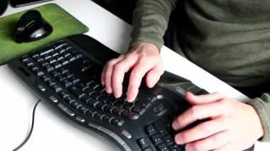 Avrupalı bir adam ev konseptinden verimli bir iş için ergonomik klavye ve ergonomik fare kullanarak klavyede bir e-posta yazıyor.