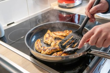 Kadın tavuk göğsü pişiriyor ve tavuklu fileto pişiriyor ve tavada fileto pişiriyor. Mutfakta sıcak et ve barbekü ile sağlıklı beslenmek için lezzetli bir yemek ve diyet yemeği.