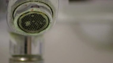Banyoda kireçlenmiş krom kabzası olarak eski pullu musluk sızıntıyı durdurmak için temizlik maddesiyle bakım ve kireçlenmeden arındırma ve damlacık yoksulluğu ile eski bakterinin hijyen bakterisini iyileştirmeye ihtiyaç duyar.