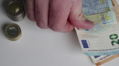 Avro banknotları ve avro paralarını sayan Avrupalı bir adam, 10, 20 ve 50 avroluk banknotlarla birlikte banknotları mali yatırım ve maaş yığını sermayesi olarak sayıyor.