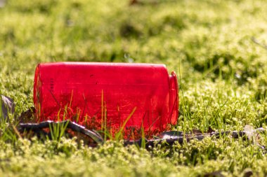 Yeşil çimlerin üzerinde kırmızı plastik şişe çöplüğü