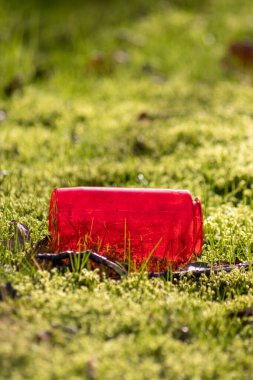 Yeşil çimlerin üzerinde kırmızı plastik şişe çöplüğü