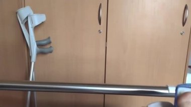 Aşil tendonu olan Avrupalı bir adam hastane yatağında özel ayakkabı ve koltuk değnekleri ile yatıyor.